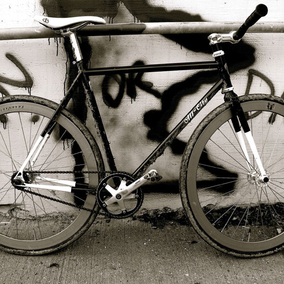 Black and white All-City Annual Volume 1 bike leaning against wall graffiti of Minnesota