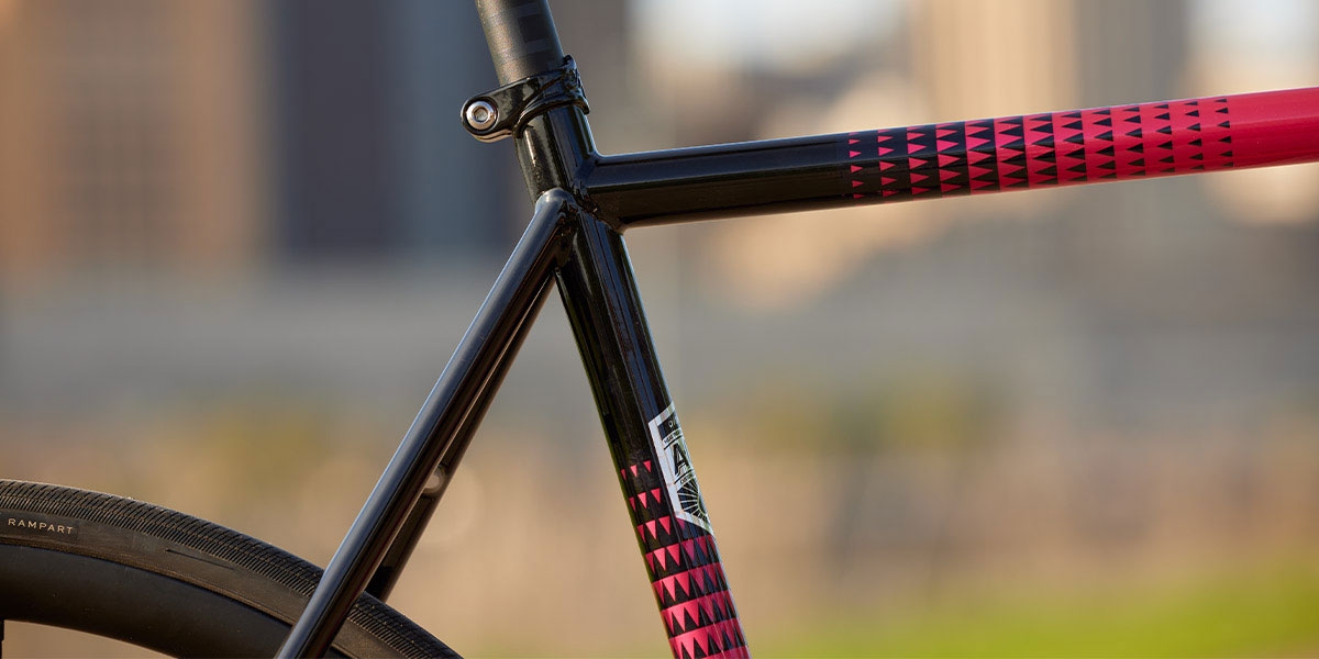 Close-up of top tube, seat tube, and seat stays of pink All-City Zig Zag Ultegra complete bike showing paint design