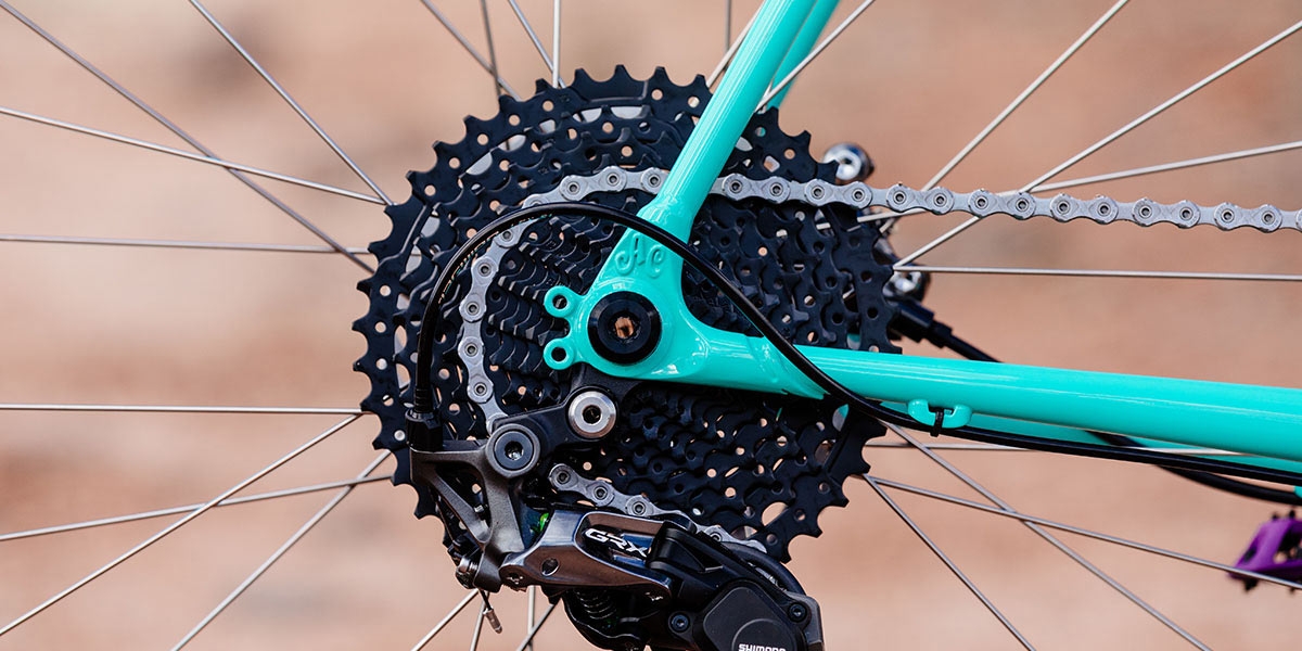 All-City Gorilla Monsoon in Aqua Seafoam color, thru-axle frame dropout on drive-side against outdoor background