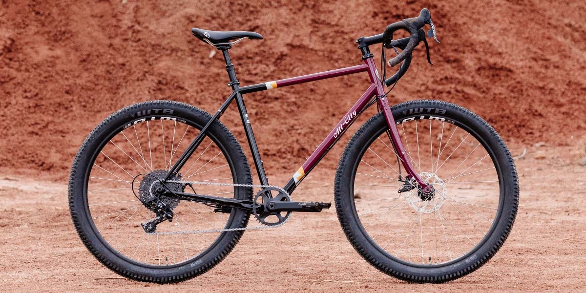 All-City Gorilla Monsoon Apex complete bike in Charred Berry color, side view against outdoor background