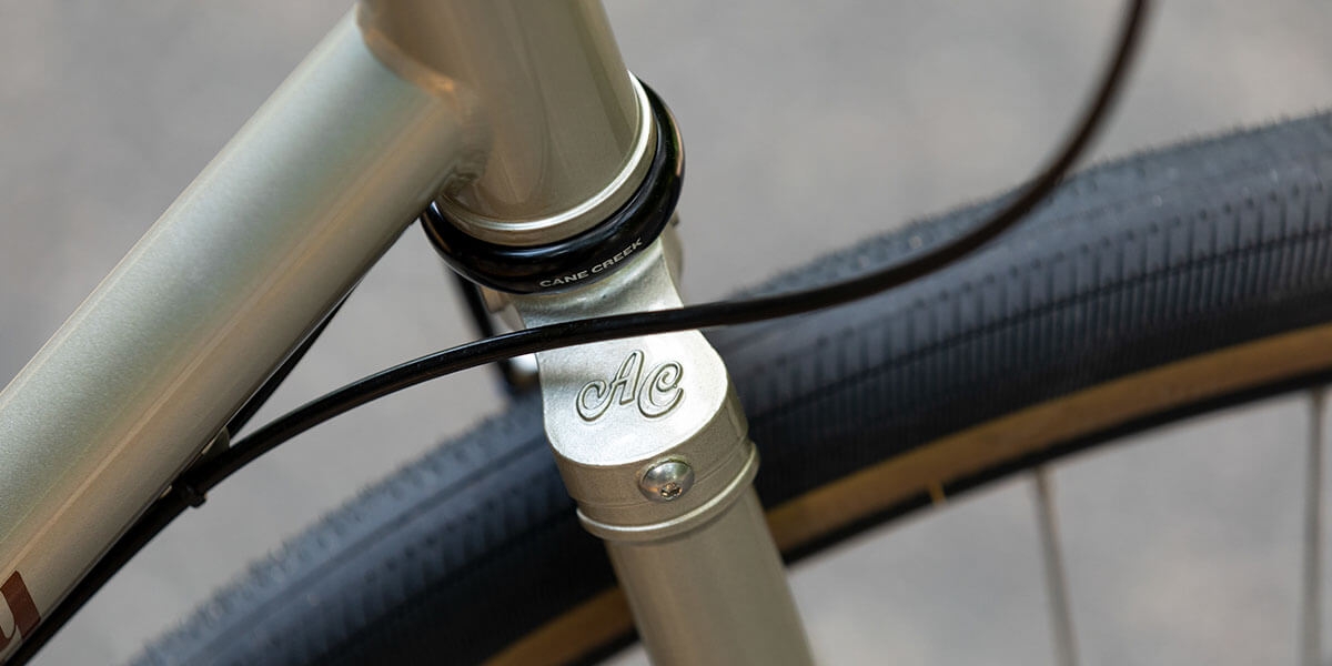 All-City gold Spacehorse bike, close-up of AC logo on fork crown