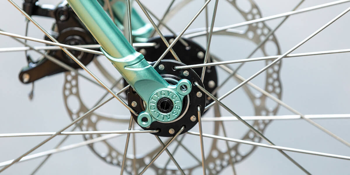 All-City green Spacehorse bike, close up fork dropout with an outdoor background