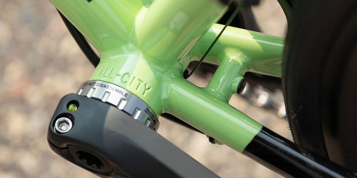 Close-up of All-City stamped in bottom bracket shell of green All-City Zig Zag 105 bike, cranks and BB installed  