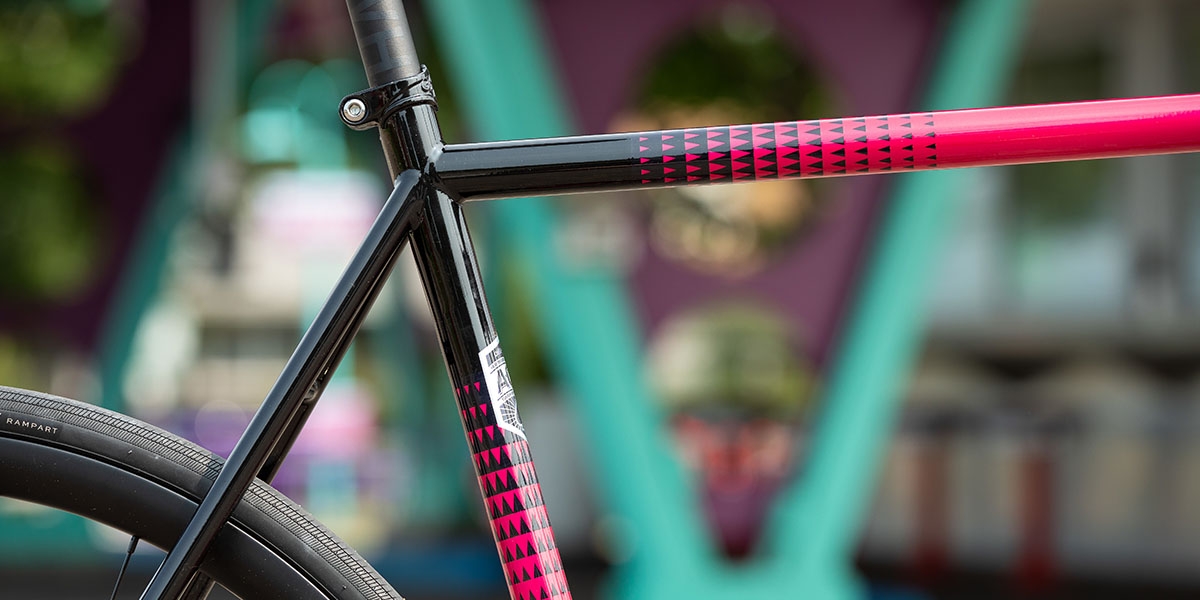 Close-up of top tube, seat tube, and seat stays of pink All-City Zig Zag Ultegra complete bike showing paint design