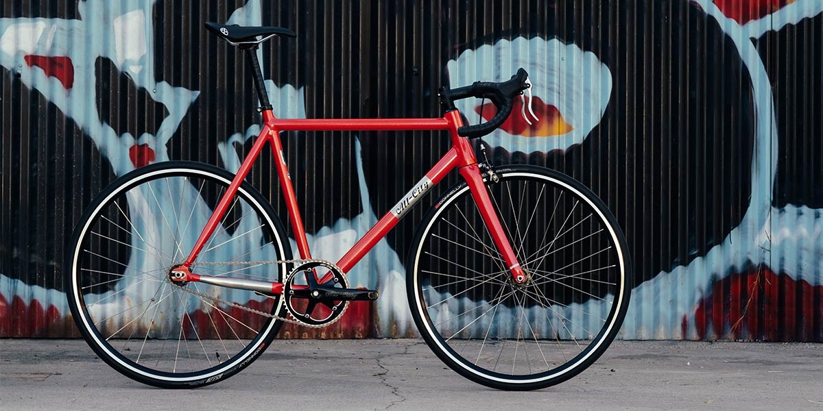Red All-City Thunderdome bike side view, leaning against a wall 

