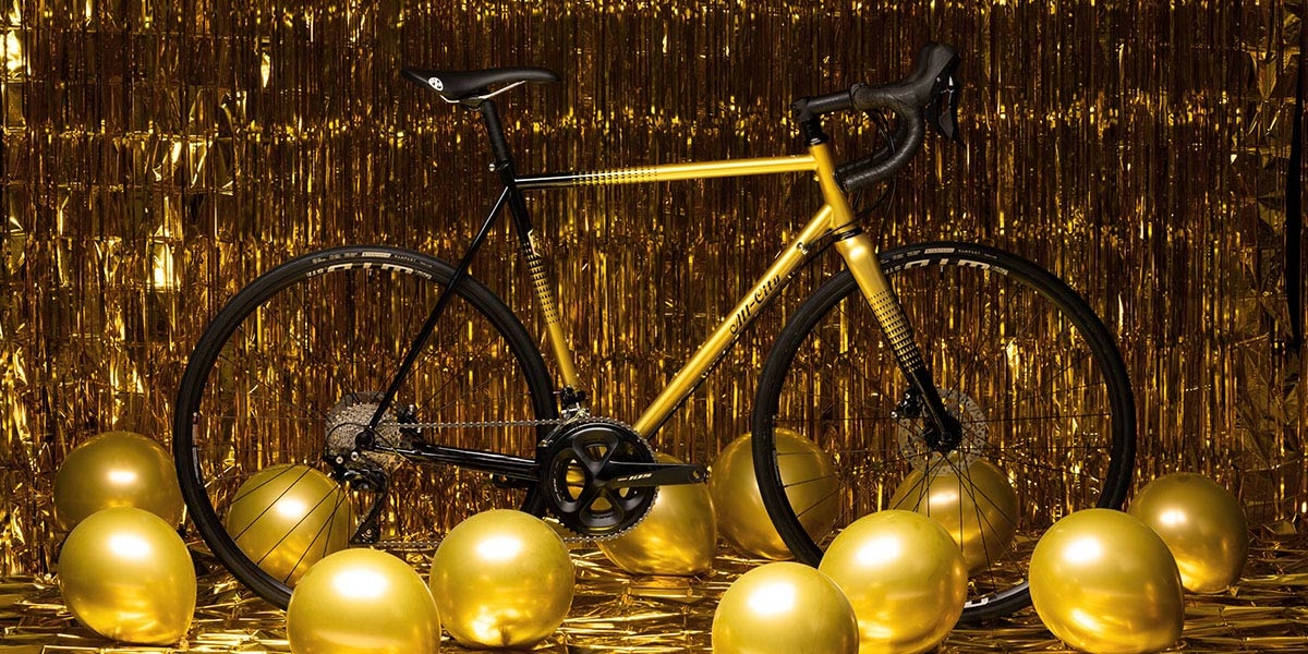 Golden Leopard All-City Cycles Zig Zag 105 complete bike side view on gold foil background and gold ballons on floor