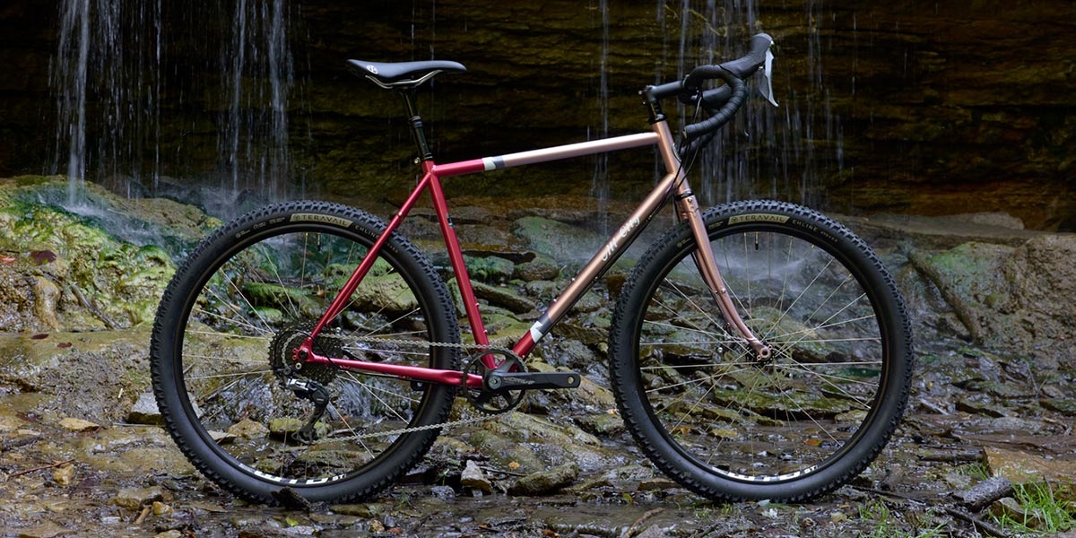 All-City Gorilla Monsoon GRX complete bike in Hotberry Rhubarb color, side view against outdoor background
