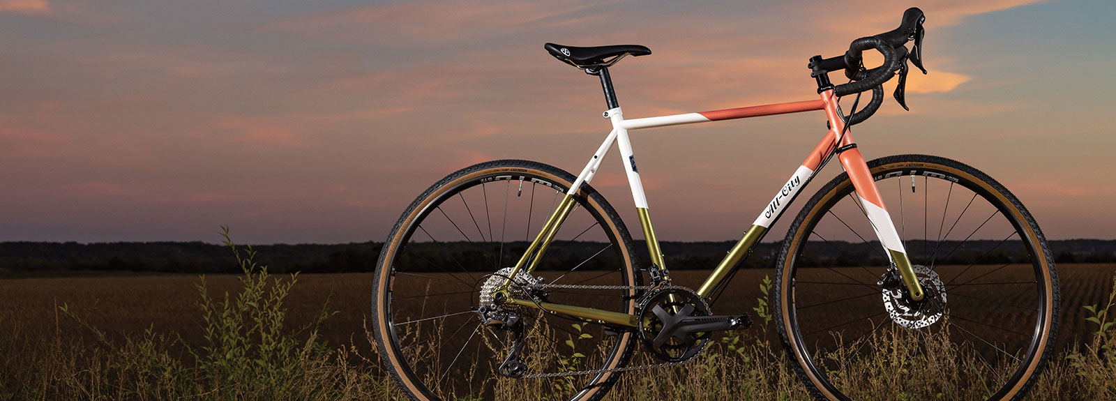 All-City Cosmic Stallion GRX Coral Moss complete bike on gravel road at sunset