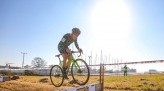 Koshi racing cyclocross and bunny hopping over barrier on clear sunny day
