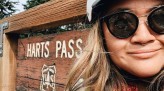 Kae-Lin Wang wearing glasses and cycling helmet, selfie in front of Harts Pass sign
