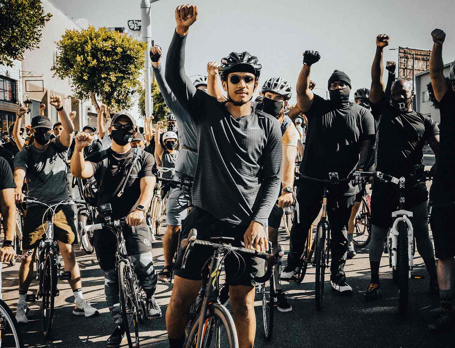 Ron Holden on a bike in a crowd with one fist raised 
