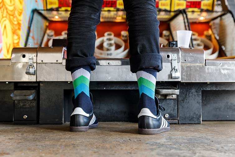 Person wears All-City cap in front of Up Down skee ball