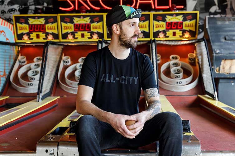 Person wears new travel tee in front of Up Down skee ball