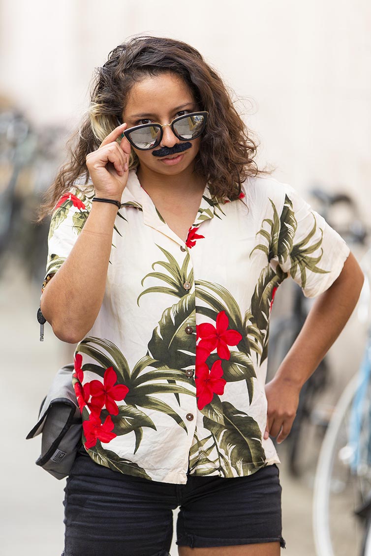 Person pulls down mustache sunglasses in Hawaiin t-shirt 