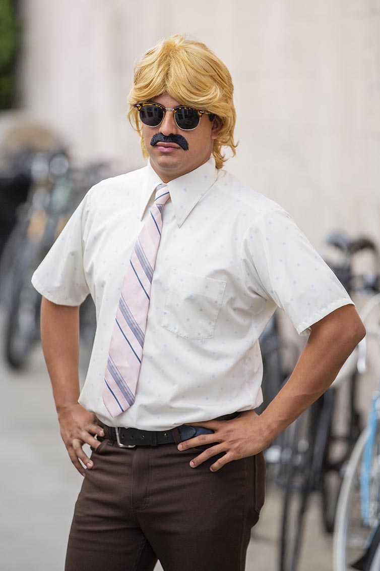 Person wears blonde wig with sunglasses and mustache