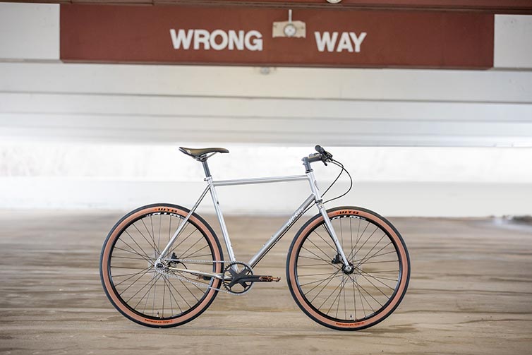 All-City Super Professional Single Speed bike side view, Quicksilver color, in empty parking garage