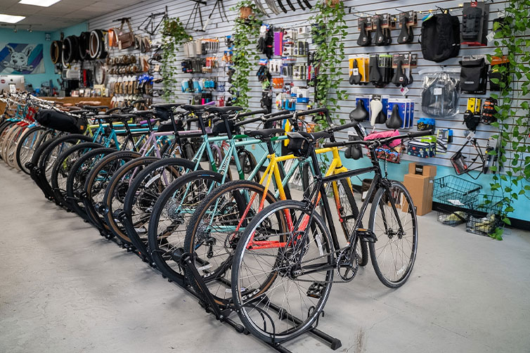 Even more All-City bike models on shop floor in front of merchandise on wall