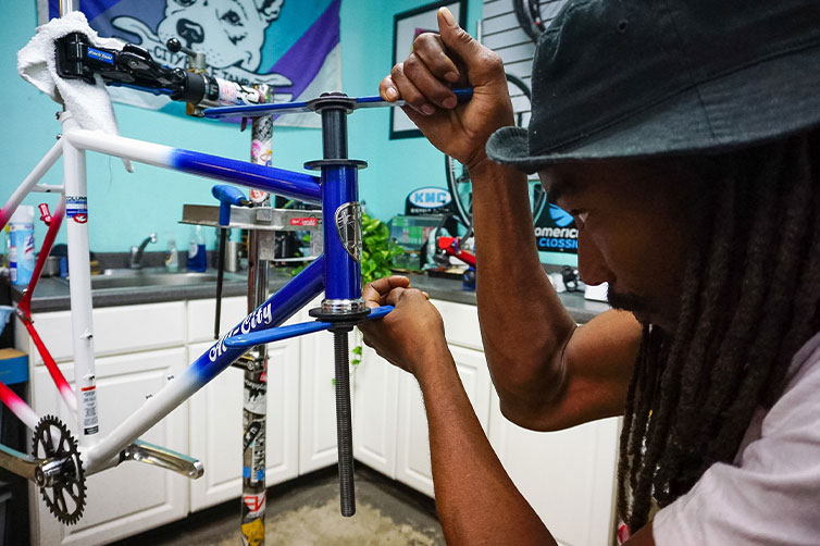 Bike mechanic pressing headset cups in All-City frame in repair stand