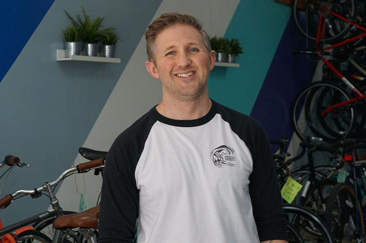 Kevin standing in front of bikes in shop smiling