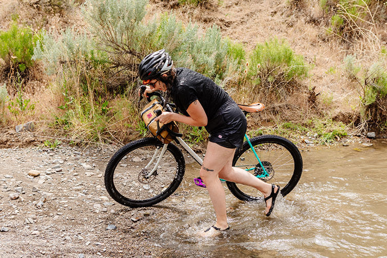 Alix pushing Gorilla Monsoon through desert stream crossing, all wet after falling in