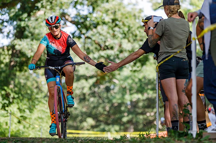 Cyclist on cyclocross race course in helmet and cycling apparel getting high-five from spectator