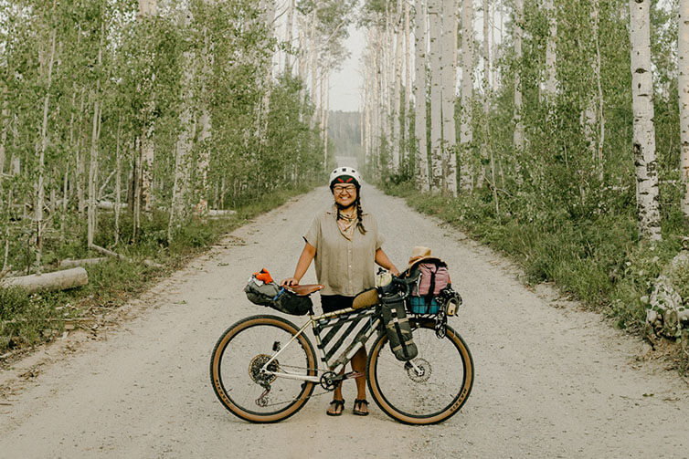 Kae-Lin Wang smiling on gravel forest road standing behind loaded Gorilla Monsoon bike