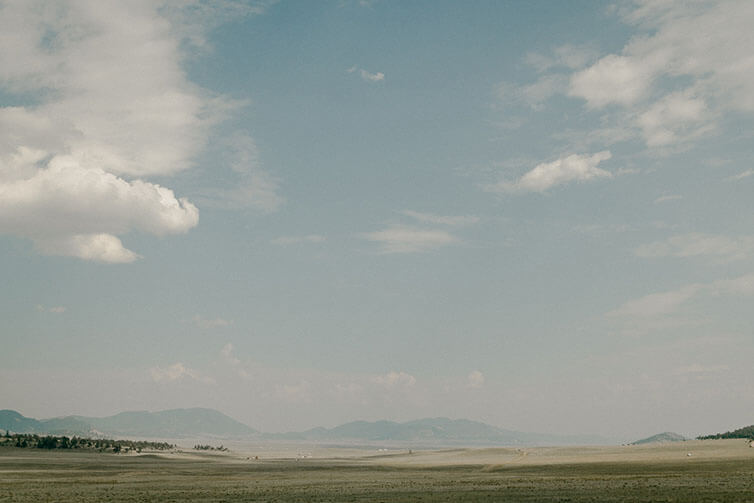 High plains on mostly sunny day, big clouds, smoke, mountains in distance