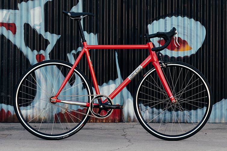 All-City Thunderdome complete bike, Hot Pink Blink, leaning against wall with graffiti