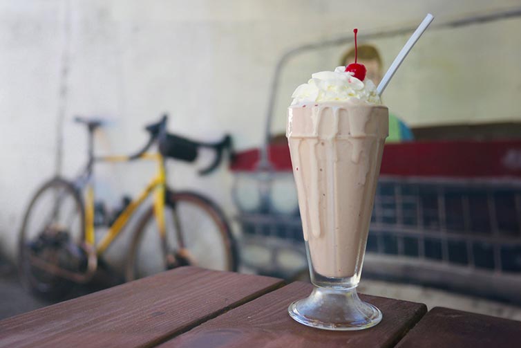 Milkshake with whipped cream and cherry on top on table