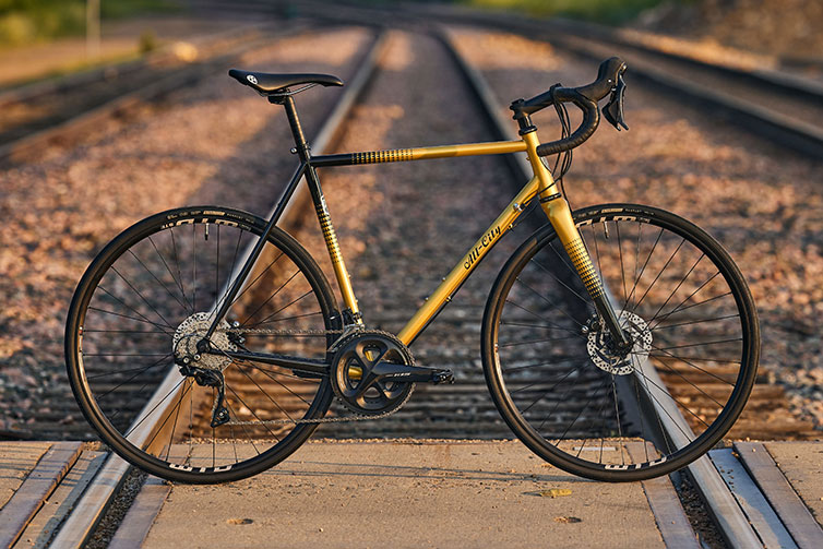 All-City Zig Zag 105 Golden Leopard bike side view on train tracks