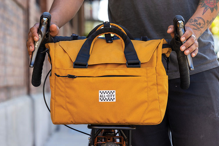 All-City Beatbox Front Rack Bag front view mounted on bike, person holding handlebars