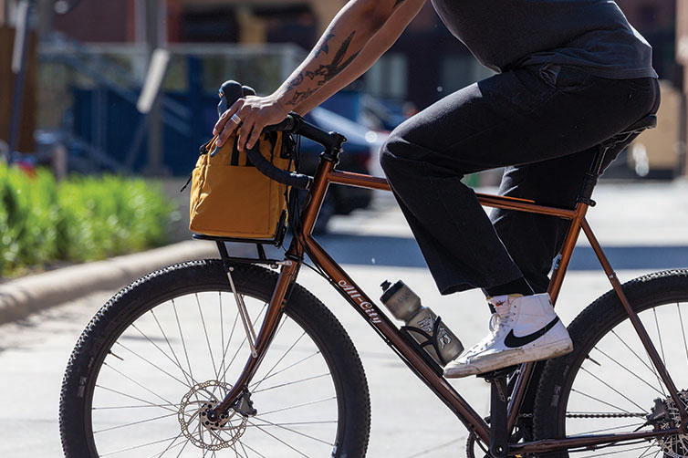 Side view of person riding bike with All-City Beatbox Front Rack Bag mounted on bike