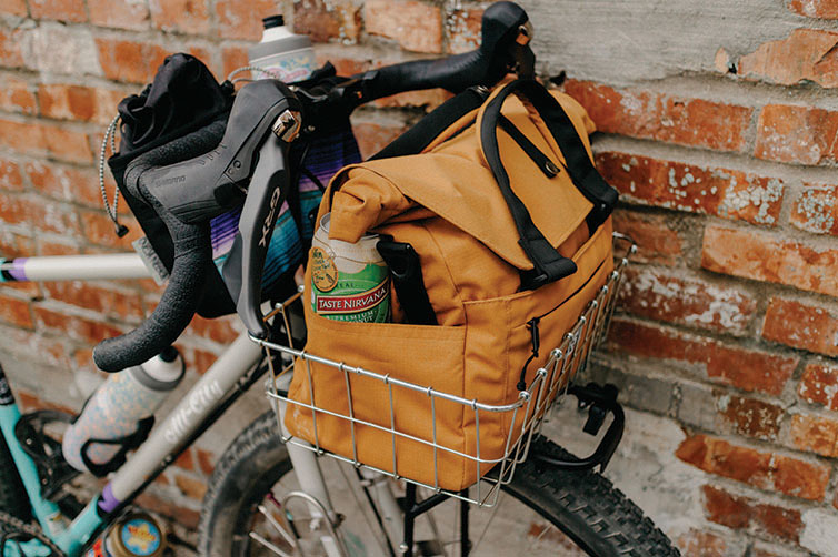 Gorilla Monsoon Bike leaning against wall with All-City Beatbox Front Rack Bag in front basket loaded with gear