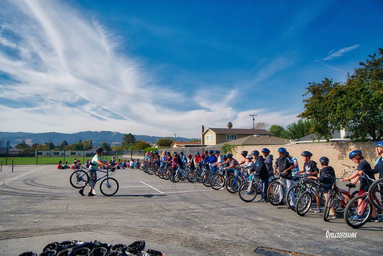 Cycles of Change bicycle skills in parking lot on sunny day with mountains in background