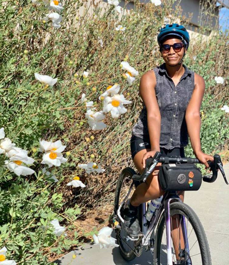 Grace Anderson stopped on her bike in front of flowers