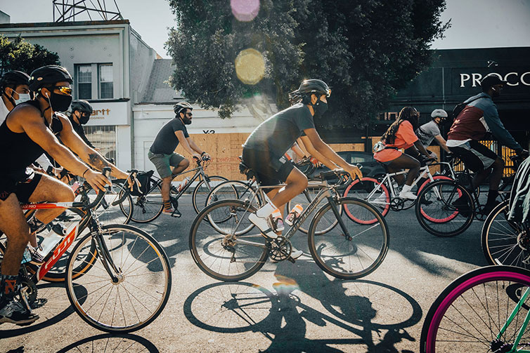 Group of cyclists, some wearing masks, some wearing helmets, during organized Ride For Black Lives ride