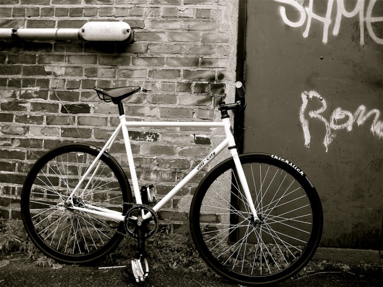 white all city bike against a brick wall 