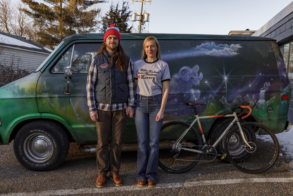 A couple standing with their bicycles and a van