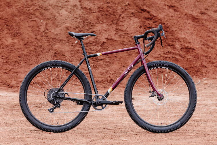 All-City Gorilla Monsoon Apex complete bike in Charred Berry color, side view against outdoor background