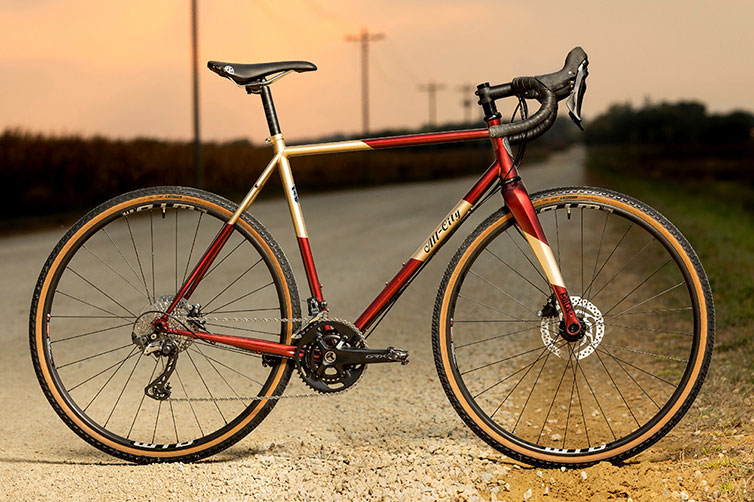 A bicycle with red and gold frame on gravel road