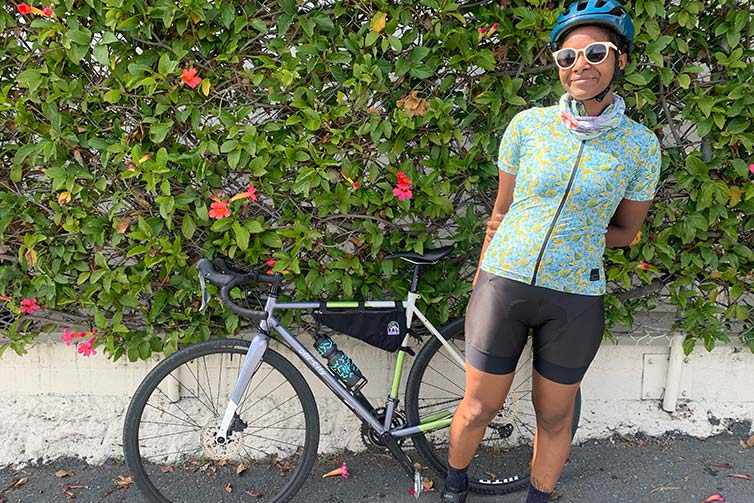 Smiling rider stands in front of bike and green background