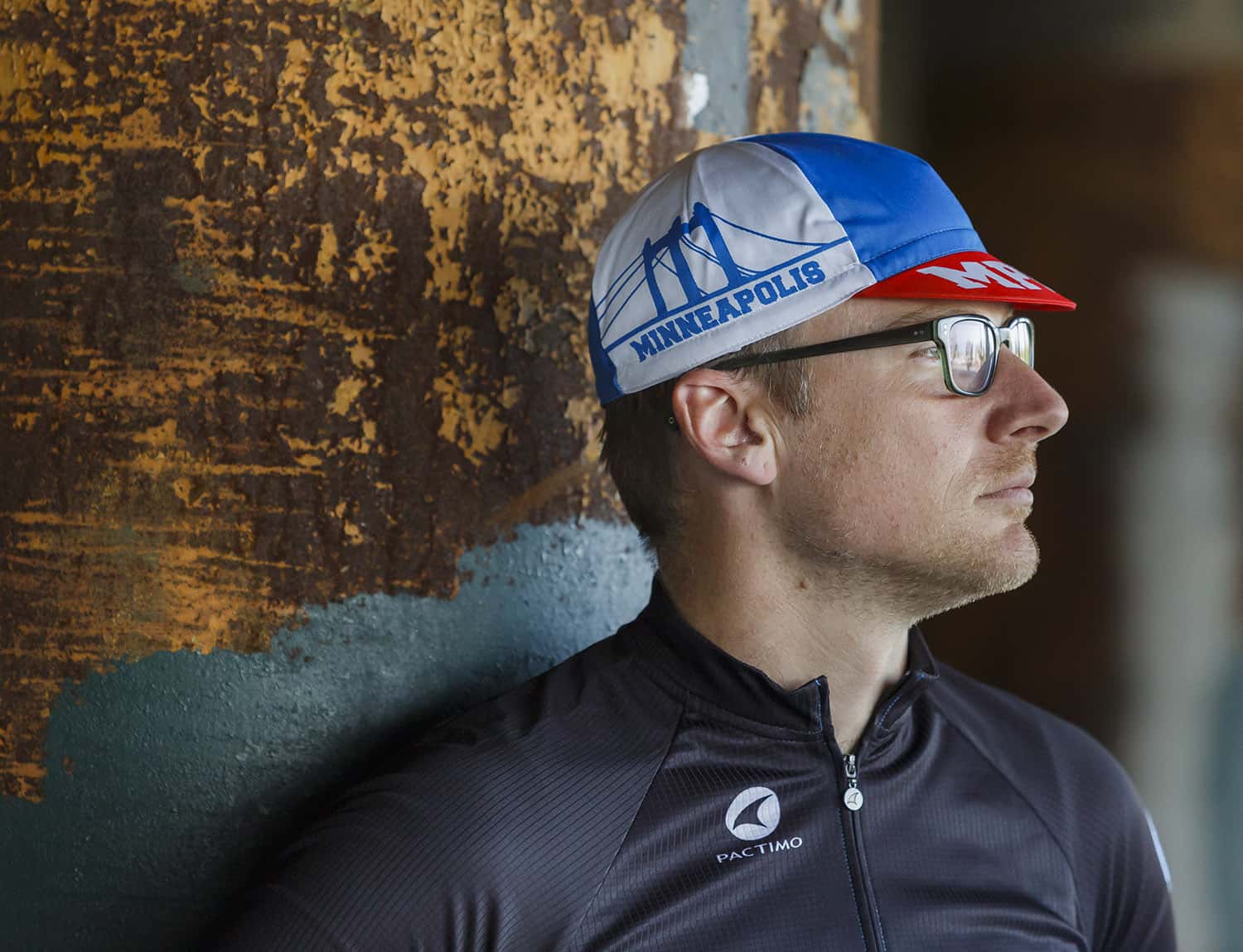 Person wearing blue, white, red Hennepin Bridge cycling cap outside