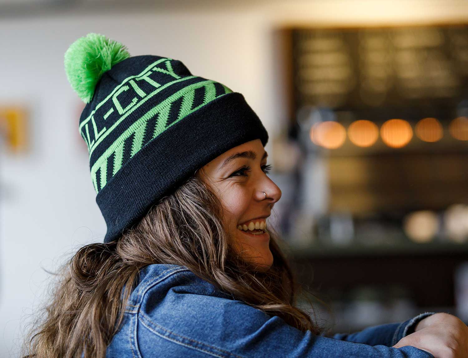 Person wearing green and black All-city Angry catfish sledding cap 