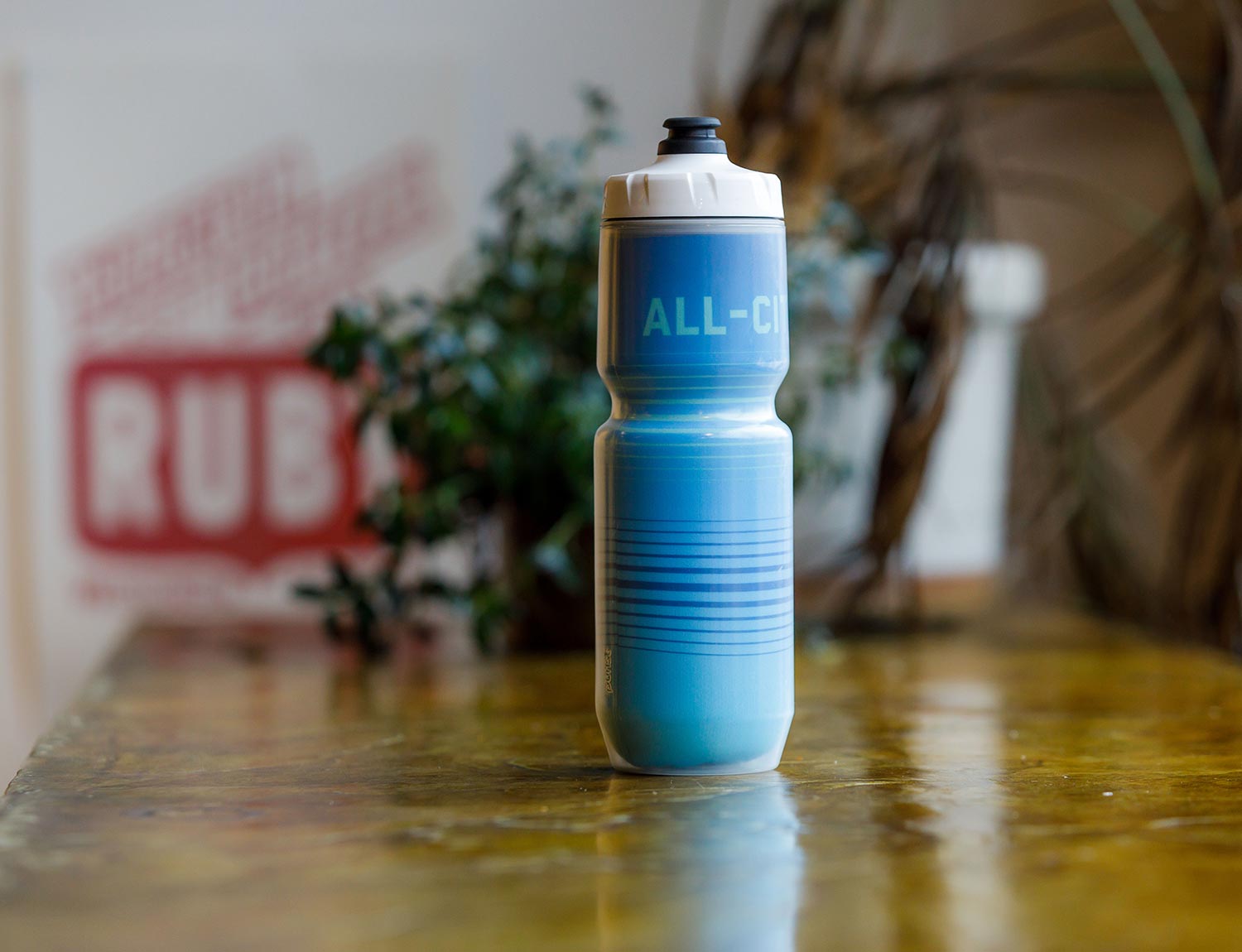 Blue All-City bright lines water bottle on table
