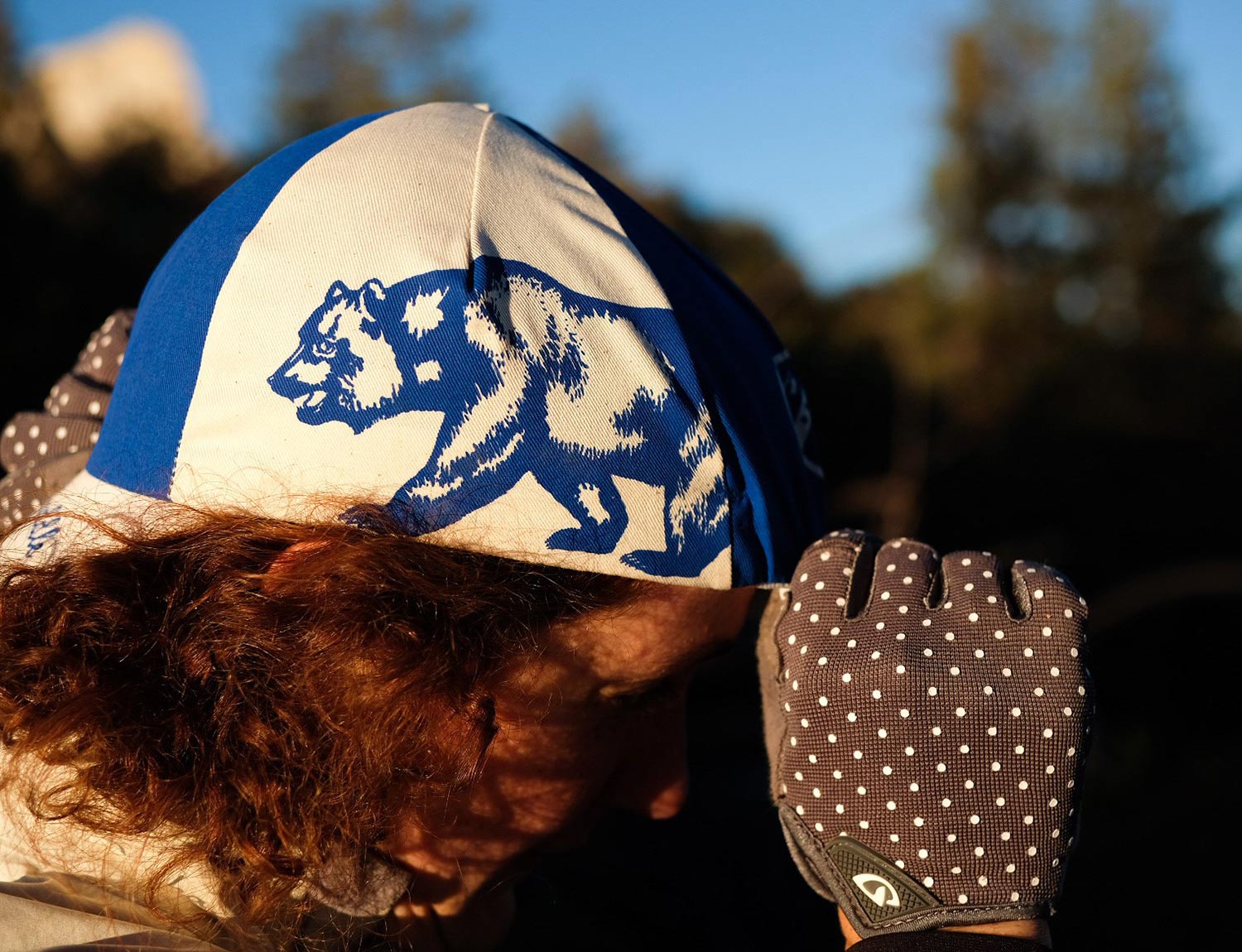 Person wearing blue and white All-City Cycles Cali Cap outside