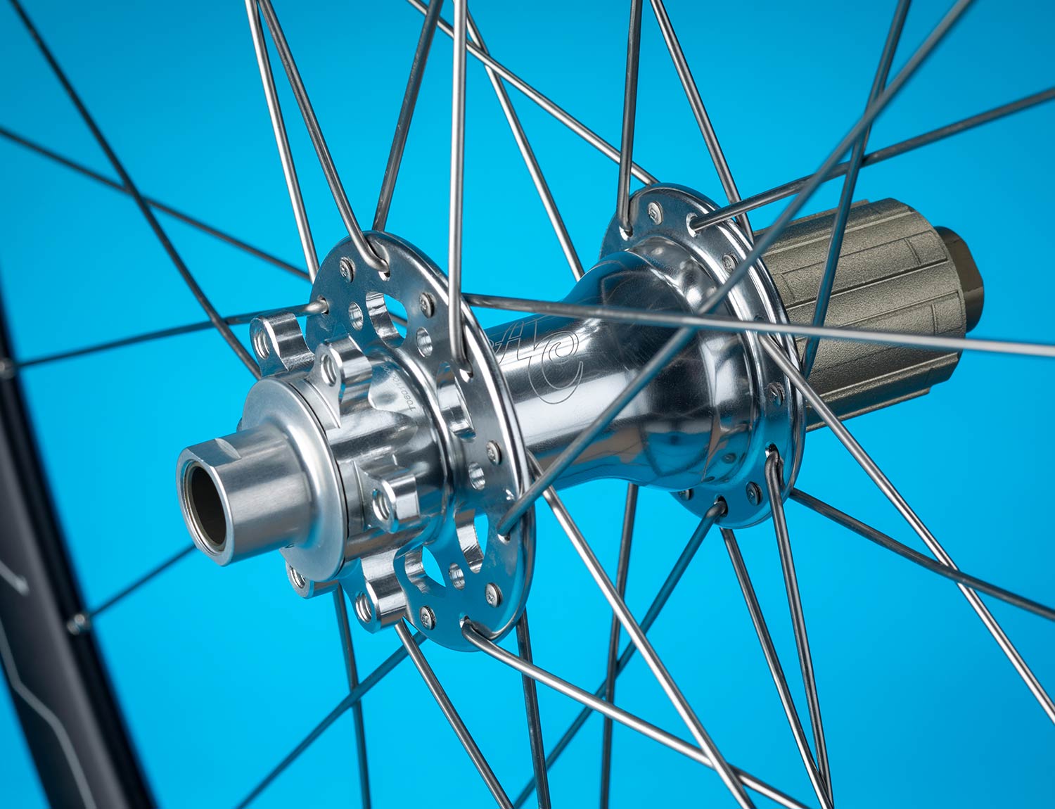 Polished silver All-City Go-Devil Rear Thru-Axle Conversion Kit on wheel with blue background