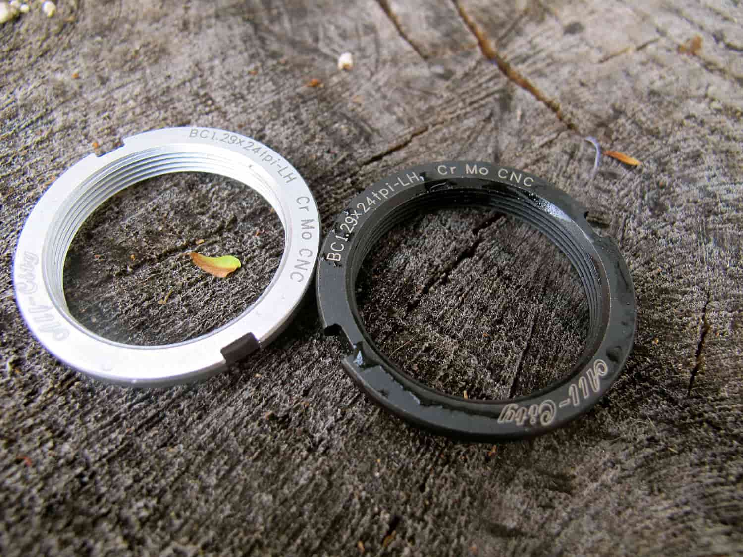 One polished silver and one black All-City Standard Lockring on wood background