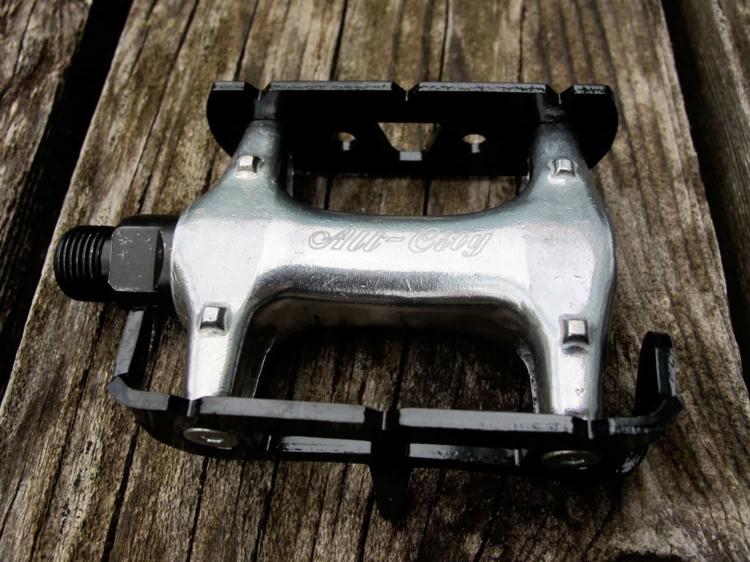 Black and polished silver standard track pedal against wood background