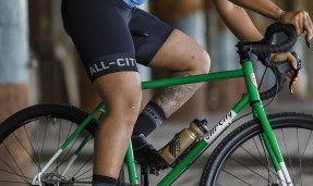 Close up person riding green bike wearing Black All-City Fast is forever wool socks 