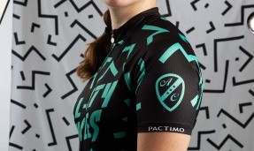 Person wearing black and teal The Max Kit jersey in front of grey abstract background